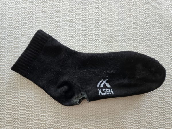 Sock with a hole worn out in the heel.